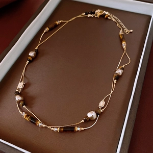 Detailed macro view of retro tiger eye and pearl double-layer necklace on jewelry tray