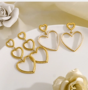 Detail of 18K gold multilayer heart drop earrings and pearl studs on ceramic tray