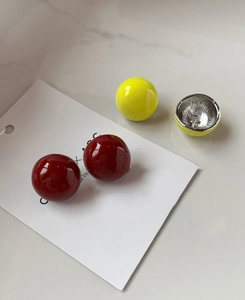 Vue détaillée des boucles d'oreilles boules rouges et jaunes sur marbre blanc