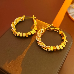 Macro view of gold hoop earrings with sparkling white pavé cubic zirconia inlay