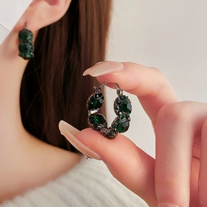 Macro shot of French vintage round hoop earrings with emerald crystals in black nickel base