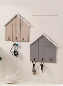 Detail of wooden house-shaped key racks with HOME lettering and three metal hooks