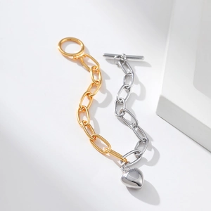 Detail of two-tone chain bracelet with silver heart pendant and toggle clasp