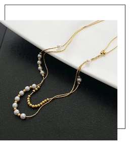 Detail view of double-layered gold titanium steel necklace with elegant white pearls