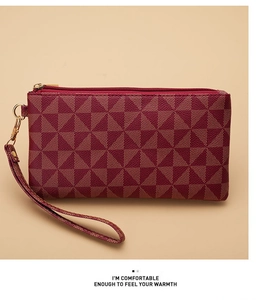 Close-up of burgundy clutch bag with geometric pattern and golden zipper detail