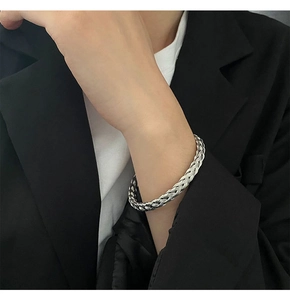 Detailed view of silver braided titanium steel bracelet on model's wrist with woven texture
