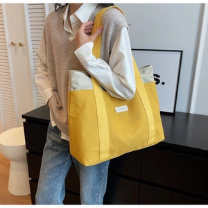 Detailed shot of yellow and beige patchwork canvas tote bag worn on shoulder by model