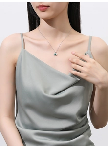 Close-up of a square green gemstone pendant necklace worn by a model on a silver chain