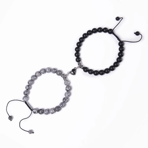 Detail of magnetic heart clasp connecting grey marble and matte black beaded bracelets