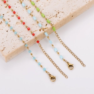 Colorful cube beads and gold stainless steel chain bracelets displayed on stone props