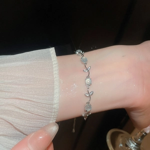 Gros plan d'un bracelet fleur papillon œil de chat en zircone sur un poignet féminin