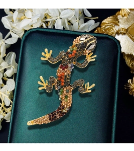 Detailed macro of gold lizard brooch featuring multi-colored crystals and gemstones