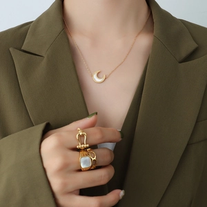 Golden moon necklace and rings with white shell inlays on a fashion model suit