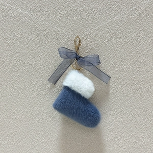 Detail of blue plush Christmas boot keychain with bow and gold metal clasp accessory
