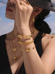 Detailed layered 18K gold stainless steel bracelets with sparkling crystals on model