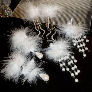 Detailed view of elegant white feather pearl earrings with rhinestones on a black background