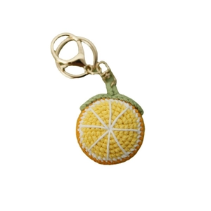 Handmade crochet orange slice keychain with green leaf detail and gold metal ring