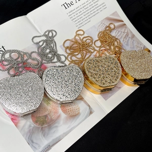 Close-up of heart-shaped rhinestone evening bags in gold and silver with metal chains