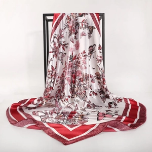 Close-up of silk-textured scarf with detailed butterfly floral prints and red geometric border