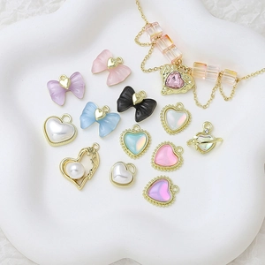 Flat lay of colorful heart and bow charms with gold chain on a white cloud tray