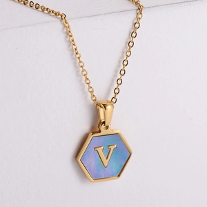 Detail of hexagonal gold pendant with blue shell inlay and letter V on fine chain