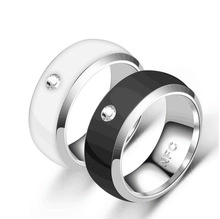 Detail view of black and white NFC smart rings with decorative stone and internal engraving