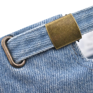 Detailed close-up of blue denim baseball cap with vintage bronze metal buckle adjustment