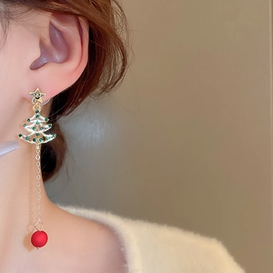 Close-up of festive Christmas tree tassel earrings with green rhinestones and red beads