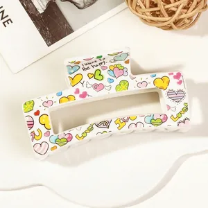 Detail of white rectangular hair claw clip with colorful heart patterns and Love text