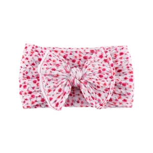 Detail of pink floral baby headband with large double-layered bow and elastic nylon fabric