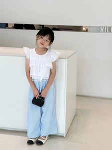 Détail de l'ensemble d'été fille avec haut en dentelle blanche et pantalon large rayé bleu