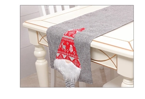 Detail of Christmas table runner featuring a grey linen texture and a red gnome motif
