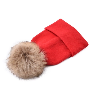 Detailed close-up of a red ribbed knit baby hat featuring a fluffy faux fur pompom
