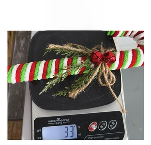 Detail view of a 33g red and white striped candy cane ornament with bells and pine needles