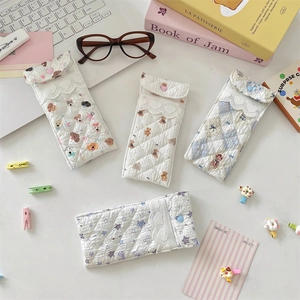 Detailed view of quilted cartoon eyeglass pouches with lace edges and heart button closures