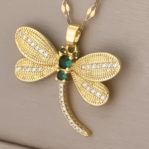 Elegant gold dragonfly necklace with sparkling green zircon and white crystals on stone