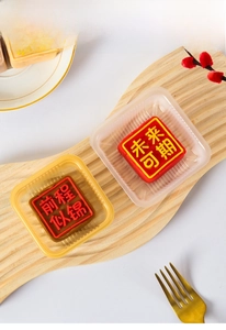 Close-up of square mooncake trays with embossed Chinese characters on wooden board