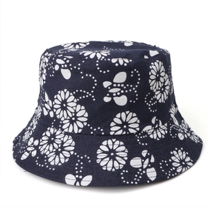Macro detail of navy cotton bucket hat featuring white floral daisy and butterfly prints