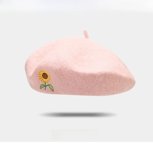 Close-up of a pink wool beret featuring detailed sunflower embroidery and soft texture