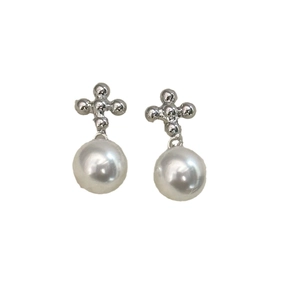 Élégantes boucles d'oreilles croix argentées avec de grandes perles blanches sur fond blanc