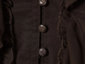 Detailed close-up of dark brown layered ruffles and matching fabric-covered buttons
