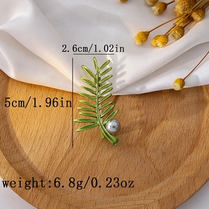 Detail view of a green leaf brooch with pearl and precise product measurements
