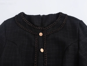 Dettaglio dello scollo in tweed nero con catena dorata e bottoni vintage in metallo