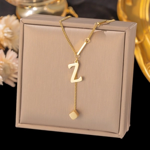 Detail of gold titanium steel necklace with letter Z pendant and square charm tassels