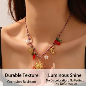 Close-up of bohemian woven necklace with gold sun, moon, and red pepper charms