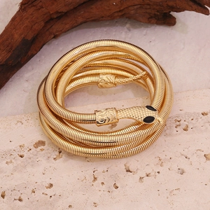 Dettaglio di un bracciale a serpente dorato a più strati con testa testurizzata su pietra