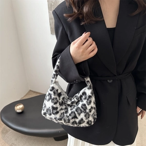 Leopard print plush shoulder bag held by model wearing a black blazer in a chic setting