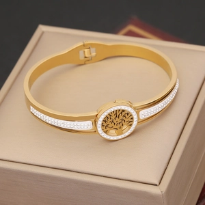 Gold stainless steel Evil Eye Tree of Life bracelet with white crystals on a beige box