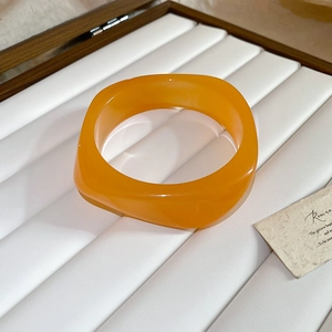 Macro detail of an orange acrylic square bracelet inside a premium wooden jewelry box