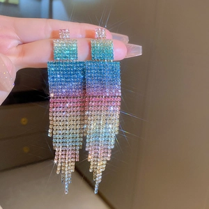Gros plan sur de longues boucles d'oreilles à pompons aux strass colorés dégradés